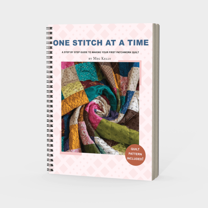 Book titled 'One Stitch at a Time' with colourful quilt image on cover